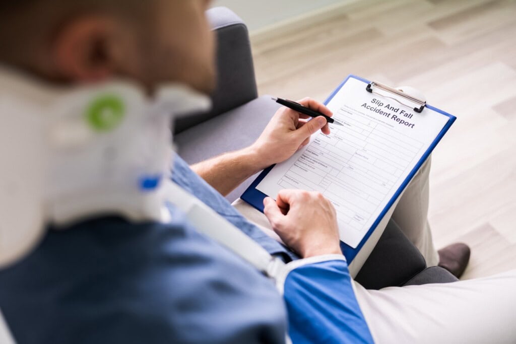 Close-up of a man with broken arm filling out health insurance claim forms