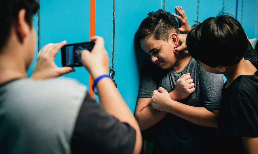 Young boy being bullied and recorded in schoo hallway