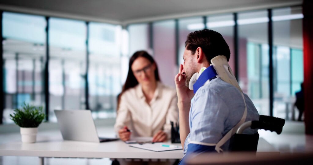 Worker with neck brace filling out injury claim forms