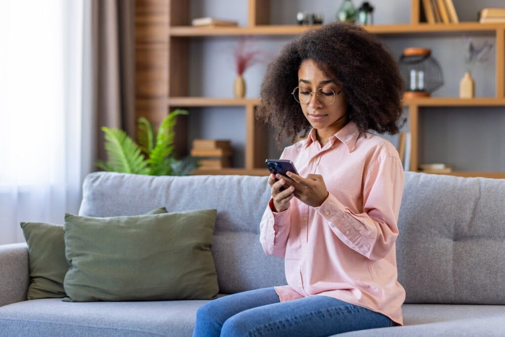 Woman using phone sitting at home in living room