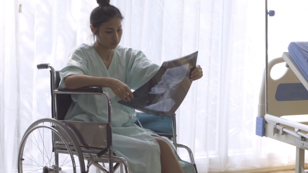 Female patient in wheelchair looking at x-ray image of her brain injury surgery.