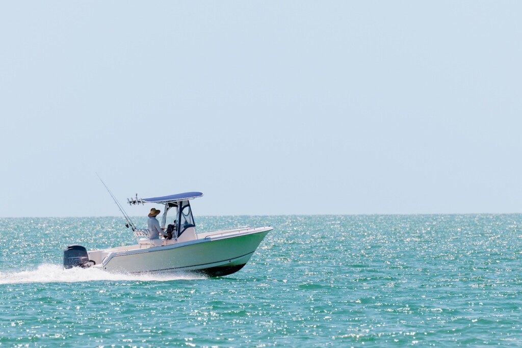White charter vessel on teal blue water offset by a pale blue, cloudless sky
